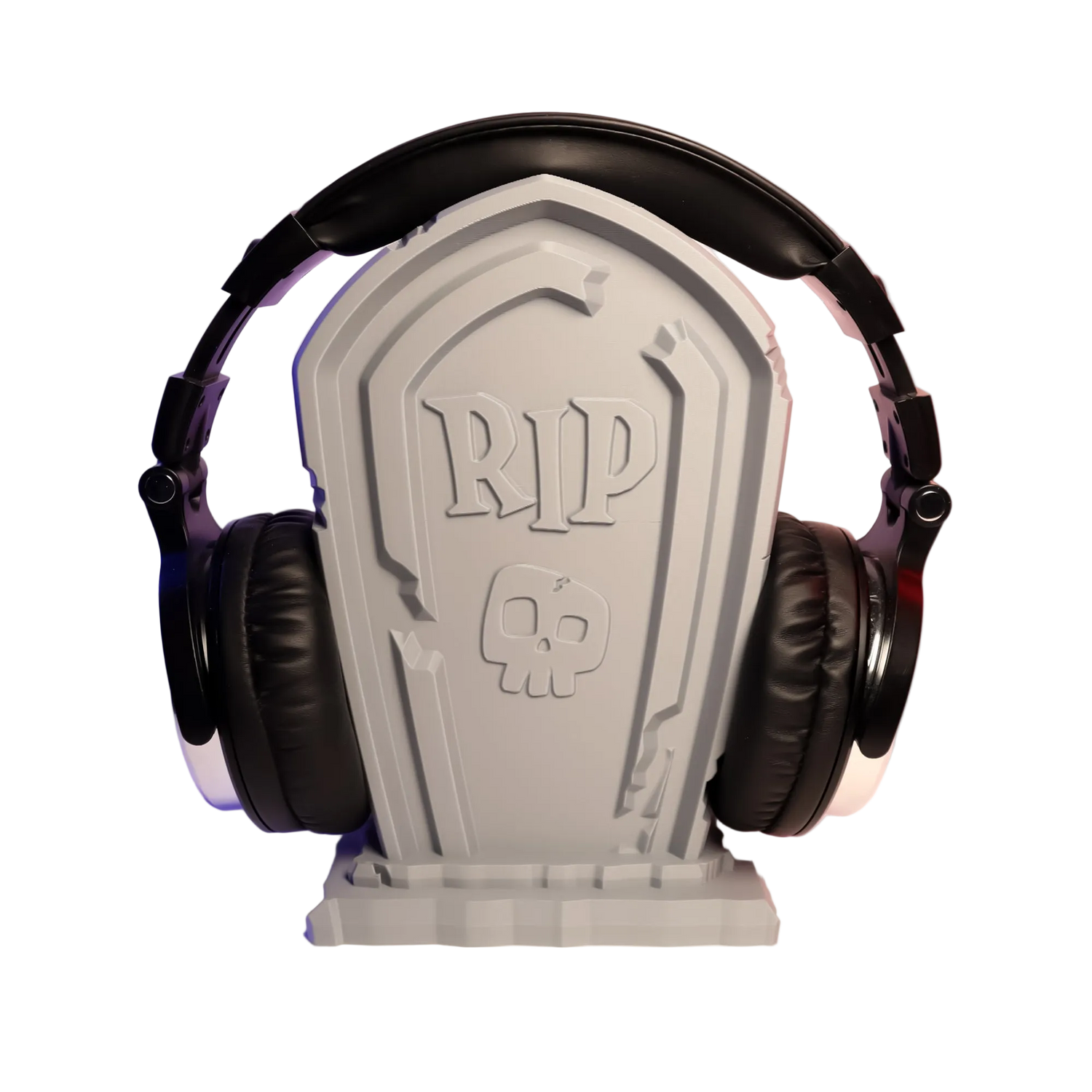 Headphones resting on a tombstone-shaped stand with 'RIP' and skull design, against a gradient background.