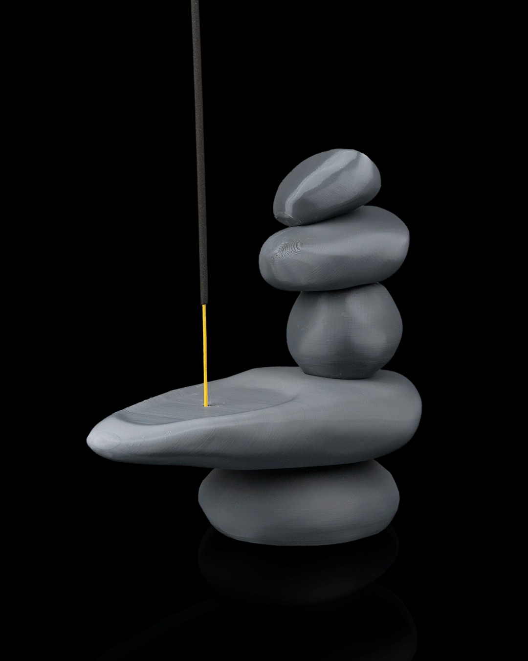 Stack of stones with a yellow stick balancing on the edge against a black background