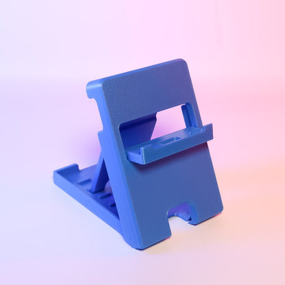 MJR Crafted blue 3D-printed foldable Nintendo Switch stand with adjustable angle and cable slot.