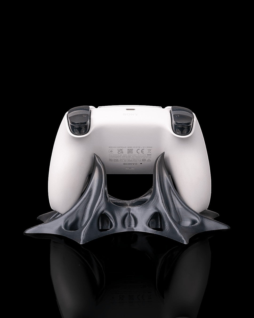 MJR Crafted modern sculptural gaming controller stand in dark grey PLA filament holding a white PlayStation controller.