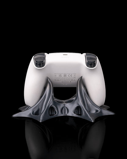 MJR Crafted modern sculptural gaming controller stand in dark grey PLA filament holding a white PlayStation controller.