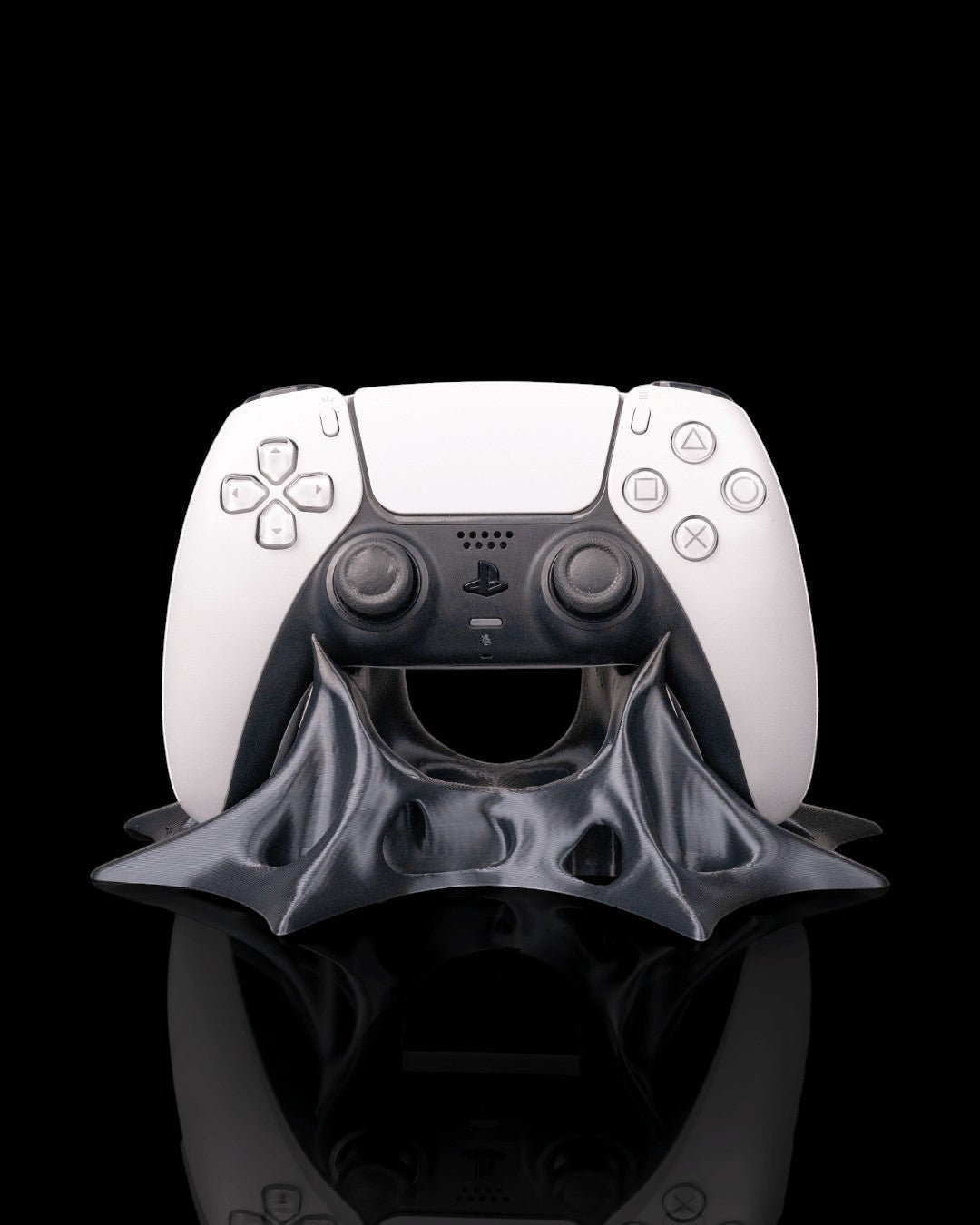 MJR Crafted modern sculptural gaming controller stand in dark grey PLA filament, holding a white PlayStation 5 controller.