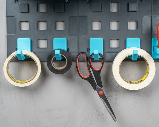 MJR Crafted modular organizer system with grey panels and bright blue hooks holding tape rolls and scissors.