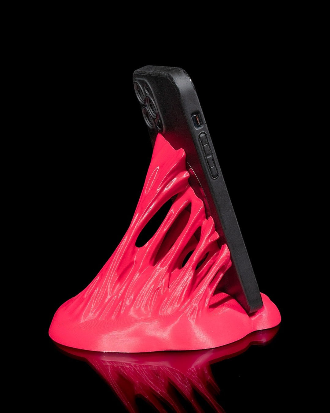 MJR Crafted hot pink 3D printed phone stand with a sculptural wave design holding a black smartphone.