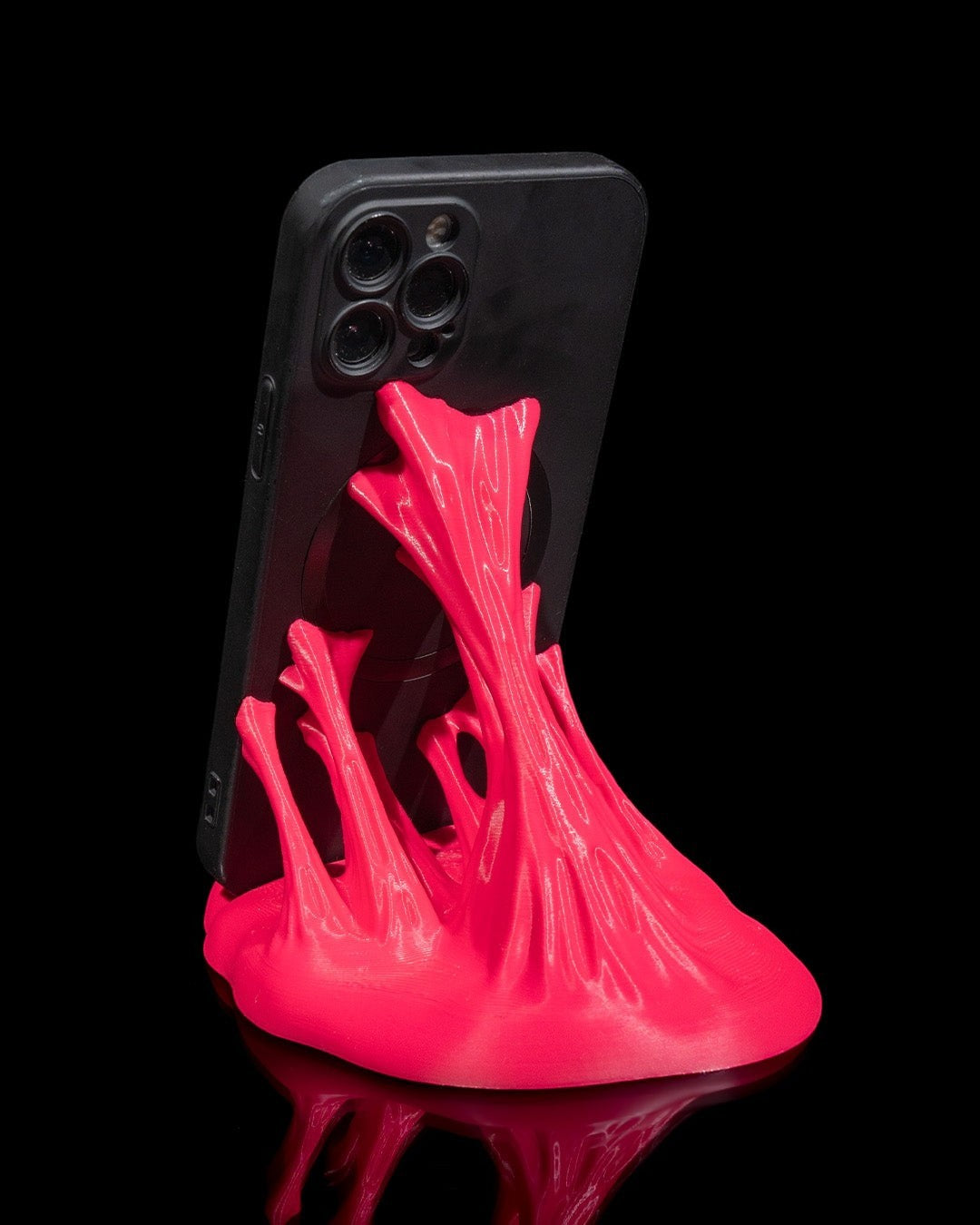 MJR Crafted bright pink 3D printed phone stand with a sculptural wave design holding a black smartphone.