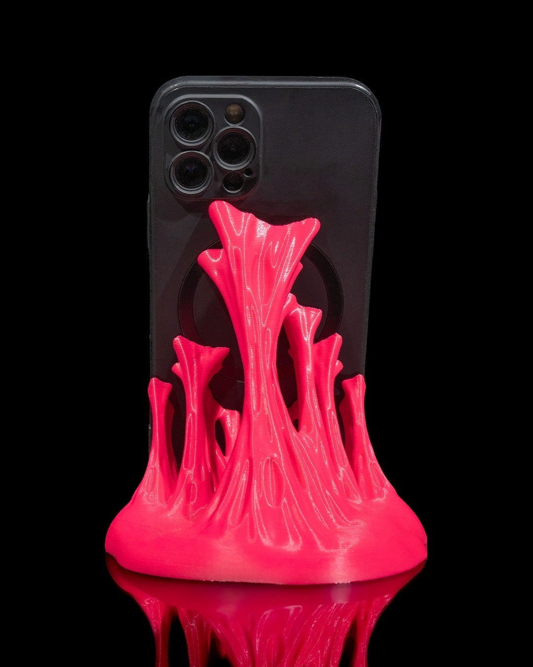 MJR Crafted bright pink sculptural wave 3D printed phone stand holding a black smartphone.