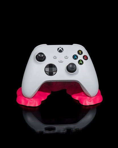 MJR Crafted white Xbox controller resting on a bright pink minimalist stand against a black background.