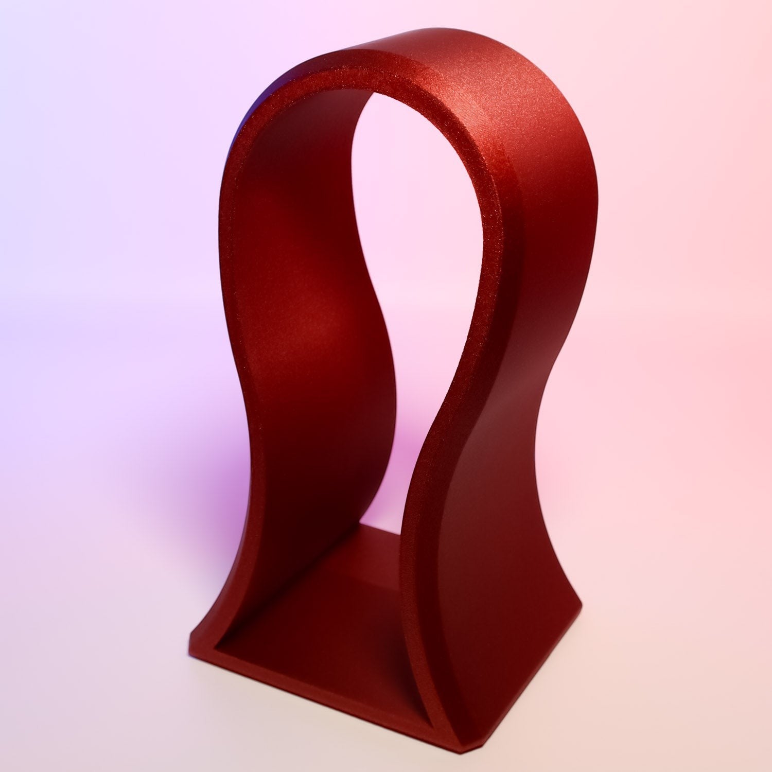 MJR Crafted red metallic sculptural headphone stand with flowing lines and a sturdy base.