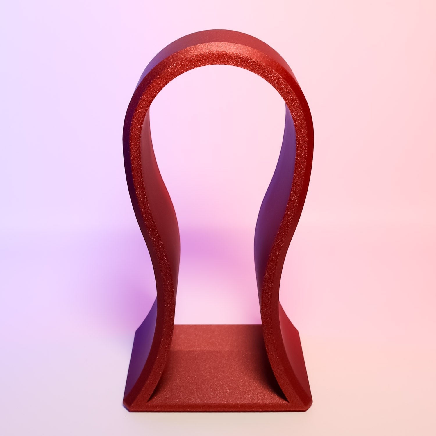 MJR Crafted red sculptural headphone stand with flowing lines and a sturdy base.
