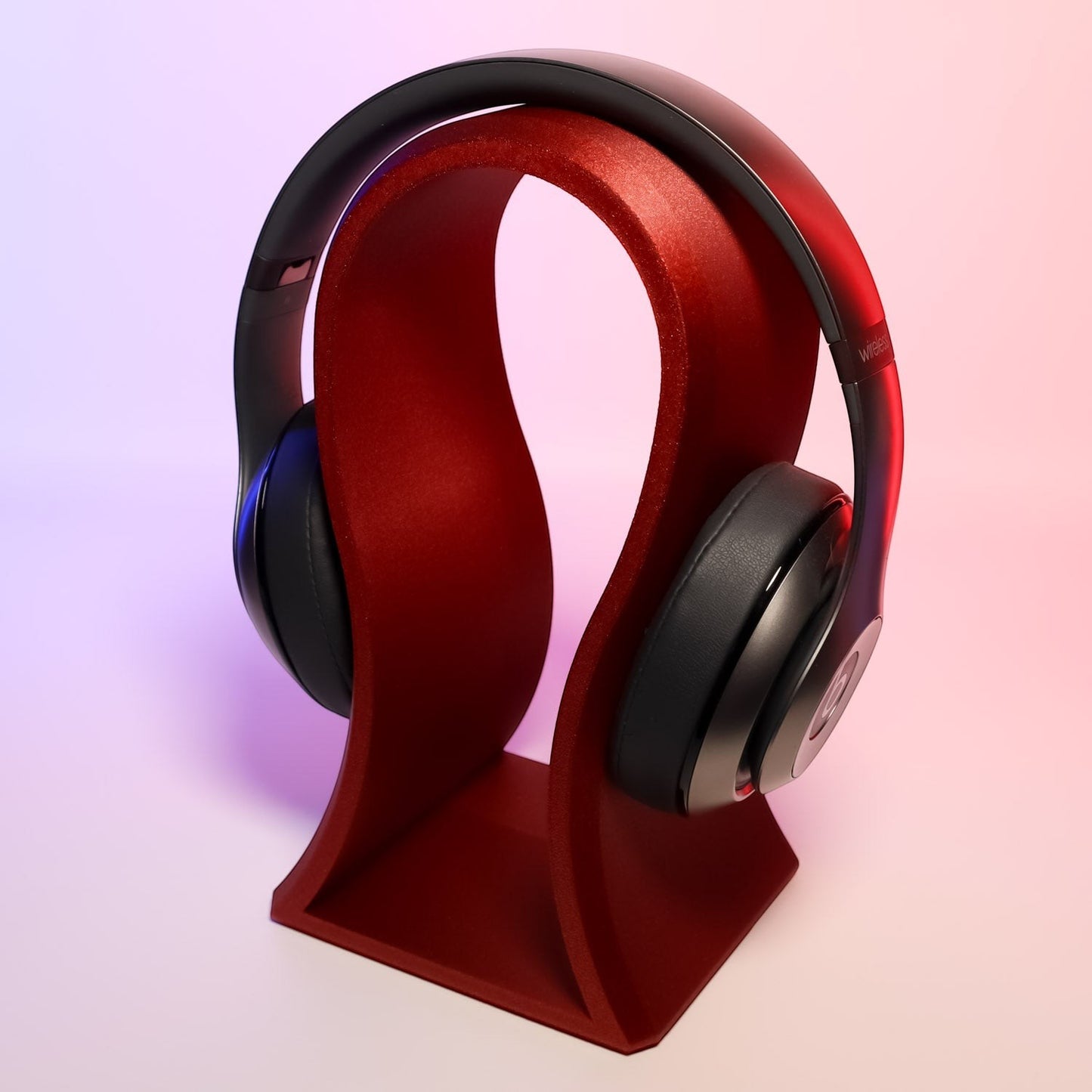 MJR Crafted red sculptural headphone stand holding black headphones. Modern desk accessory.