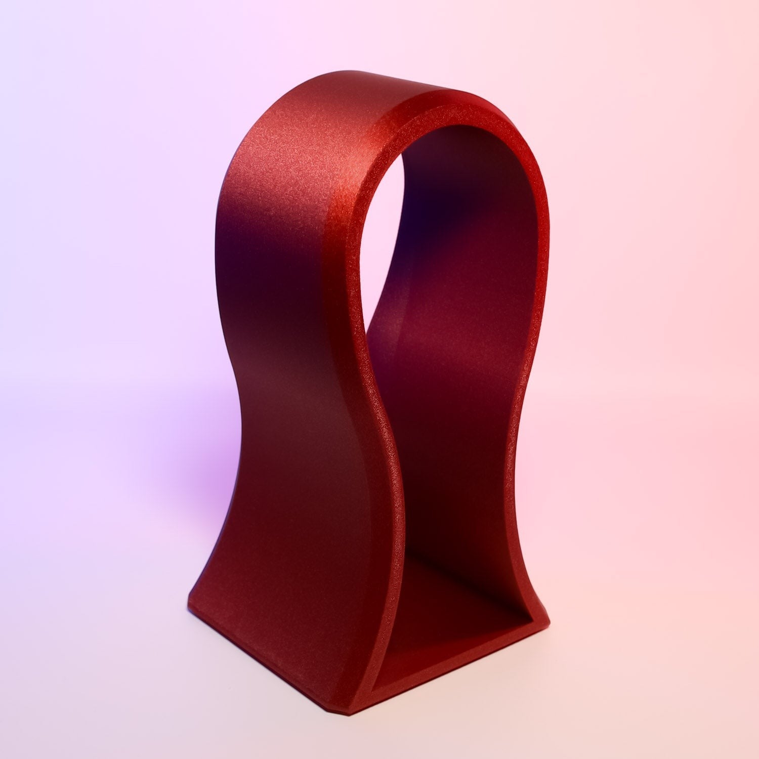 MJR Crafted red sculptural headphone stand with flowing lines and a sturdy base, perfect for desk display.