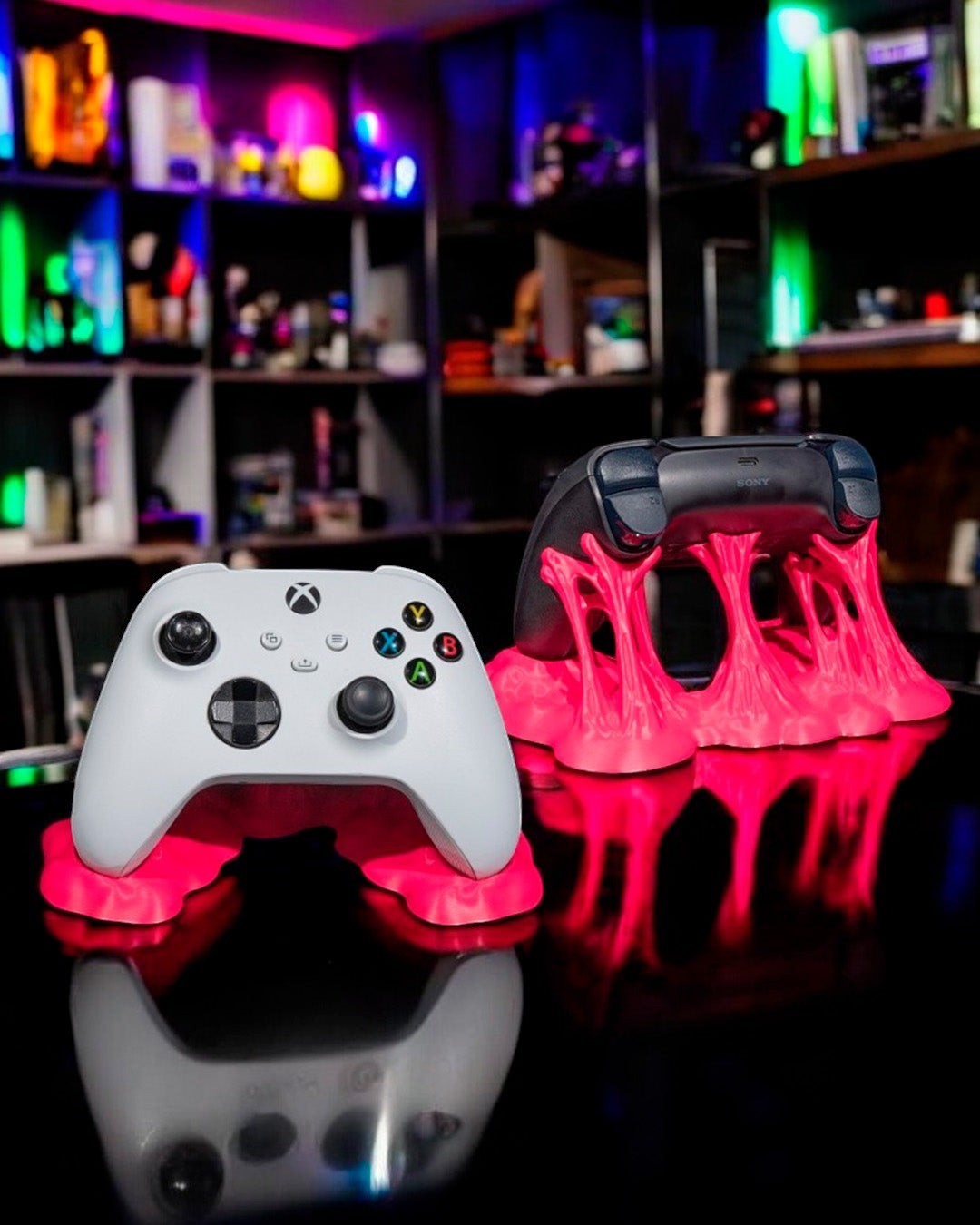 MJR Crafted pink sticky controller stand holding a white Xbox controller and a black PS5 controller.