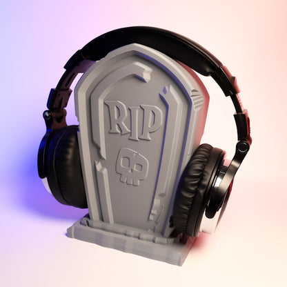 MJR Crafted grey tombstone headphone stand with RIP and skull design, holding black headphones.
