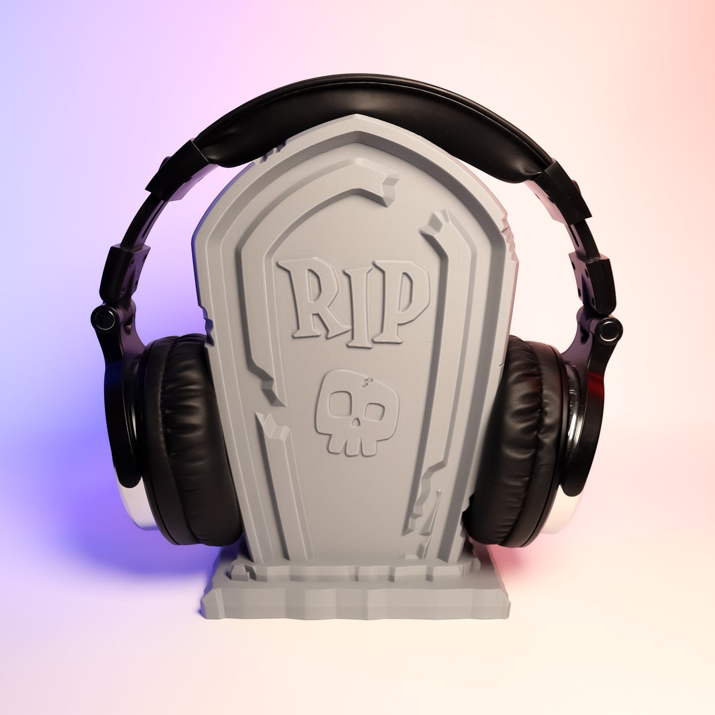MJR Crafted Tombstone headphone stand in grey, featuring RIP and a skull design. Holds black headphones.