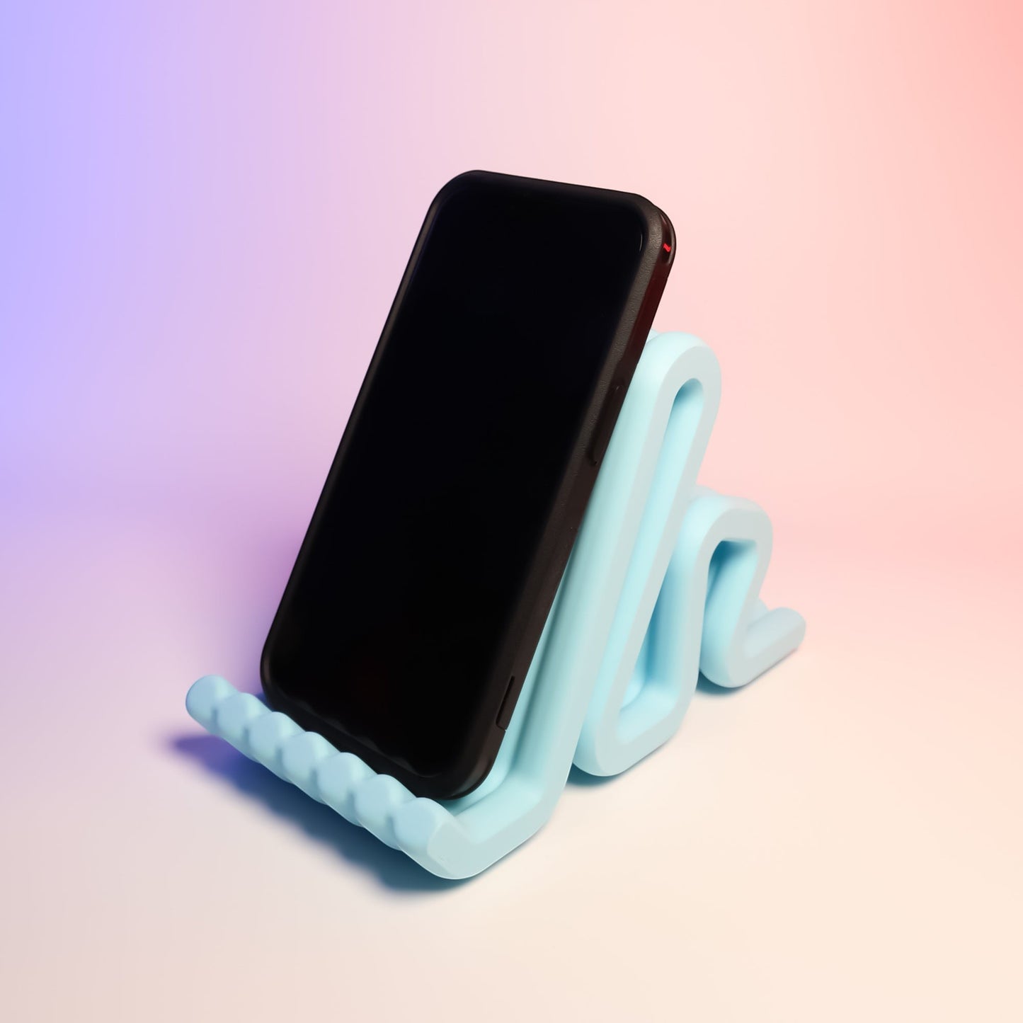 MJR Crafted light blue wavy phone stand holding a black smartphone, perfect for desks.