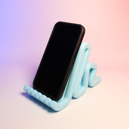 MJR Crafted light blue wavy phone stand holding a black smartphone, perfect for desks.